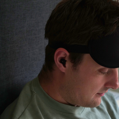 Man wearing a black sleep mask and silicone earplugs. 